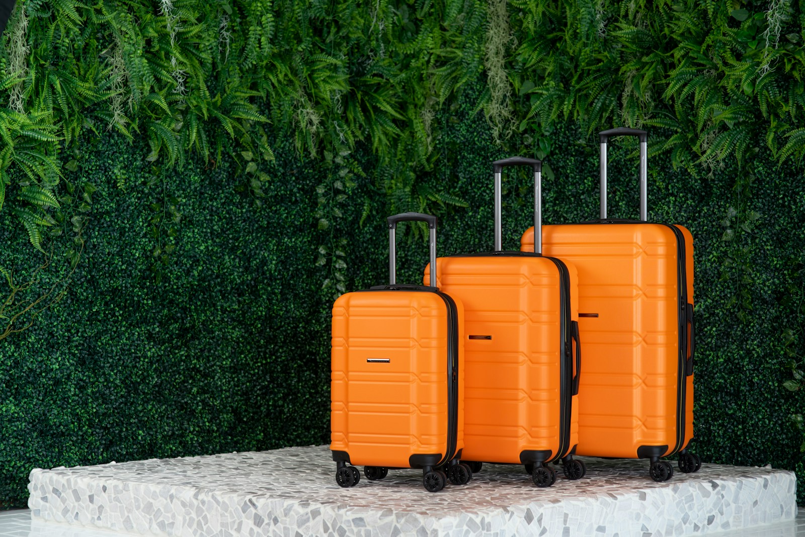 three orange suitcases sitting on a pedestal in front of a green wall